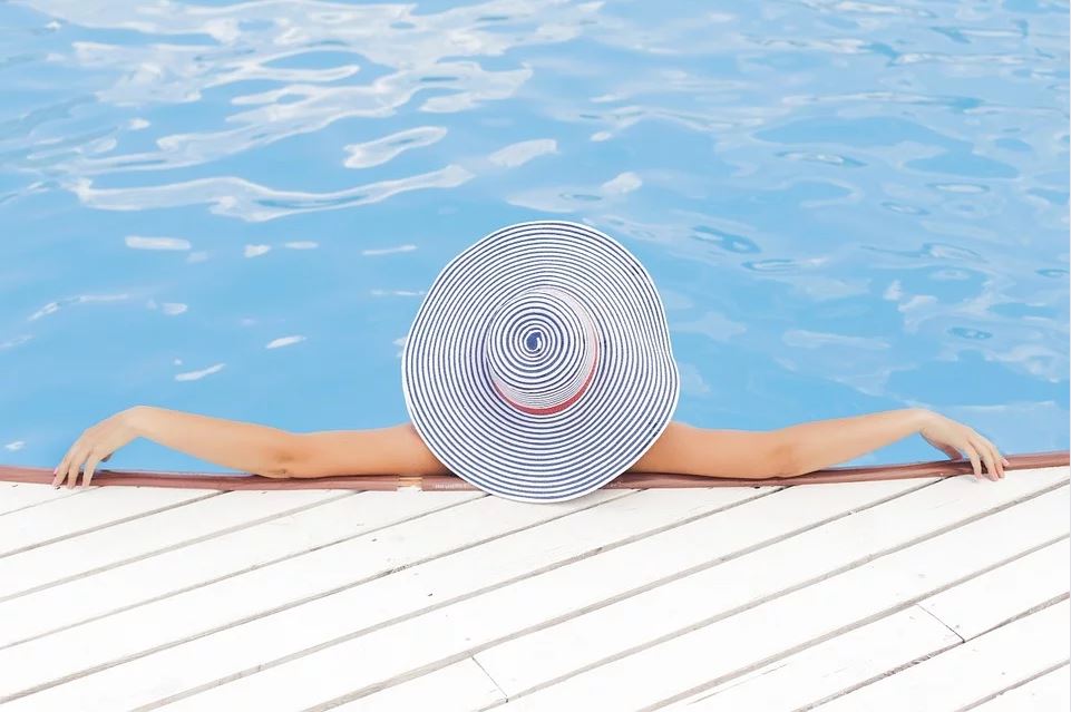 Jeune femme qui se fait bronzer au bord de sa piscine